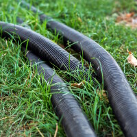 Foto das zeigt, wie Wellrohre im Gras eingelegt sind.