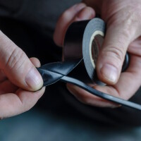 Foto das zeigt, wie ein Kabel mit Reparaturband isoliert wird.