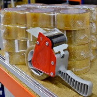 Foto eines Abrollers vor einem Stapel Klebebänder.